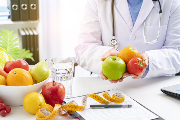 Primer plano de un nutricionista sosteniendo frutas y verduras