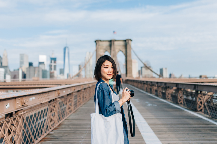 female-tourist-taking-picture-on-brooklyn-bridge