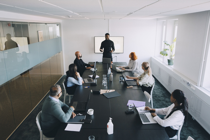 high-angle-view-of-businessman-giving-presentation-colleagues-in-board-room-at-office