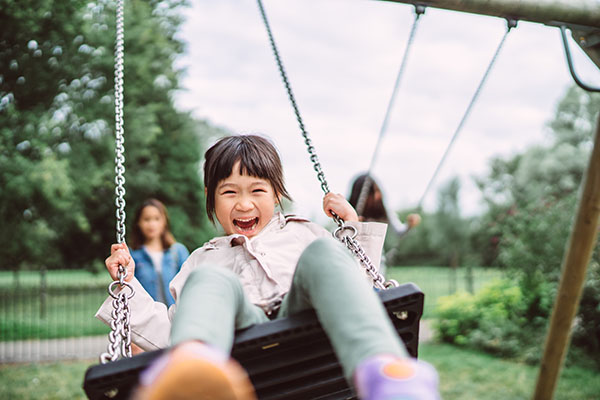 lovely-little-girl-smiling-at-the-camera-while-playing-on-a-swing-set-in-playground-joyfully portadaensenanza